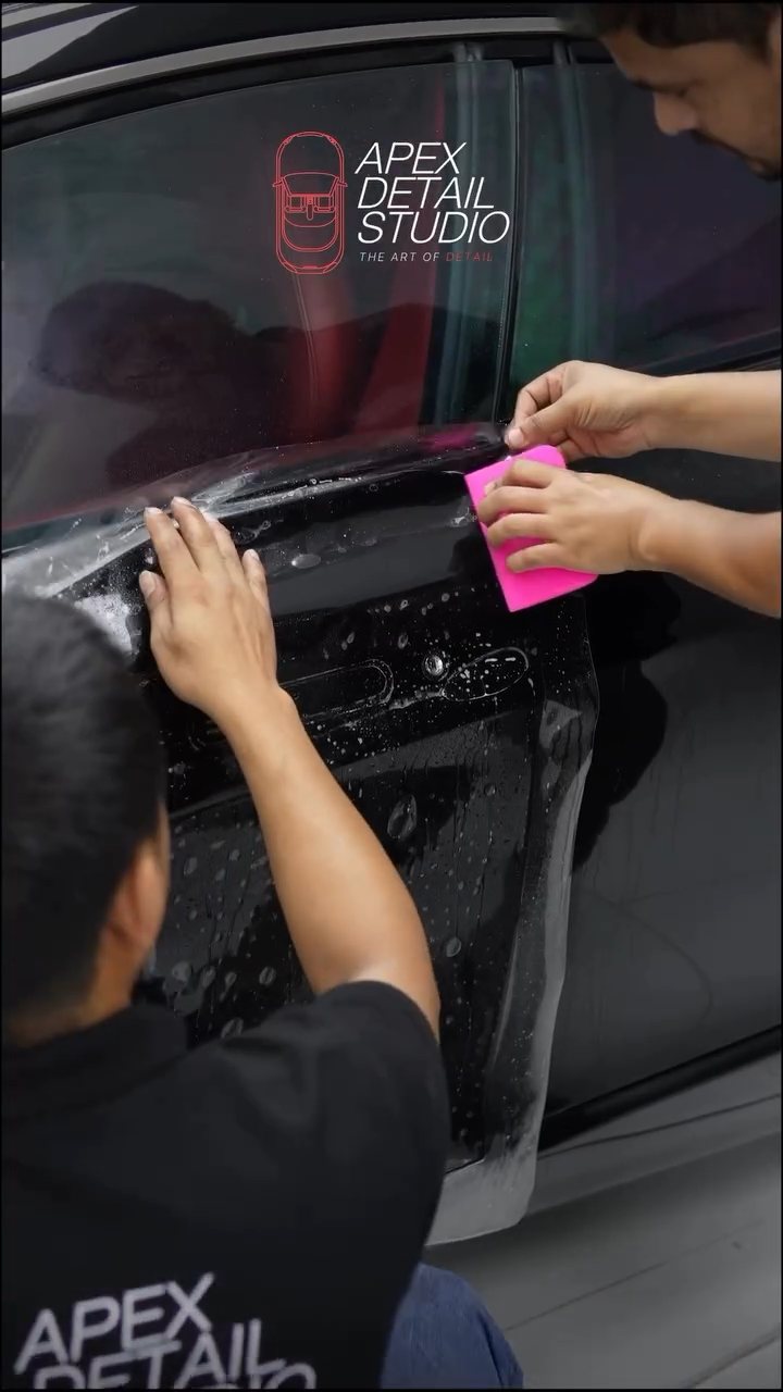 Installers squeegeeing PPF on the Aston Martin Rapide door at Apex Detail Studio
