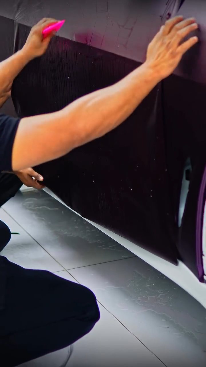 Installer fitting purple colour PPF to the BMW X5 lower door