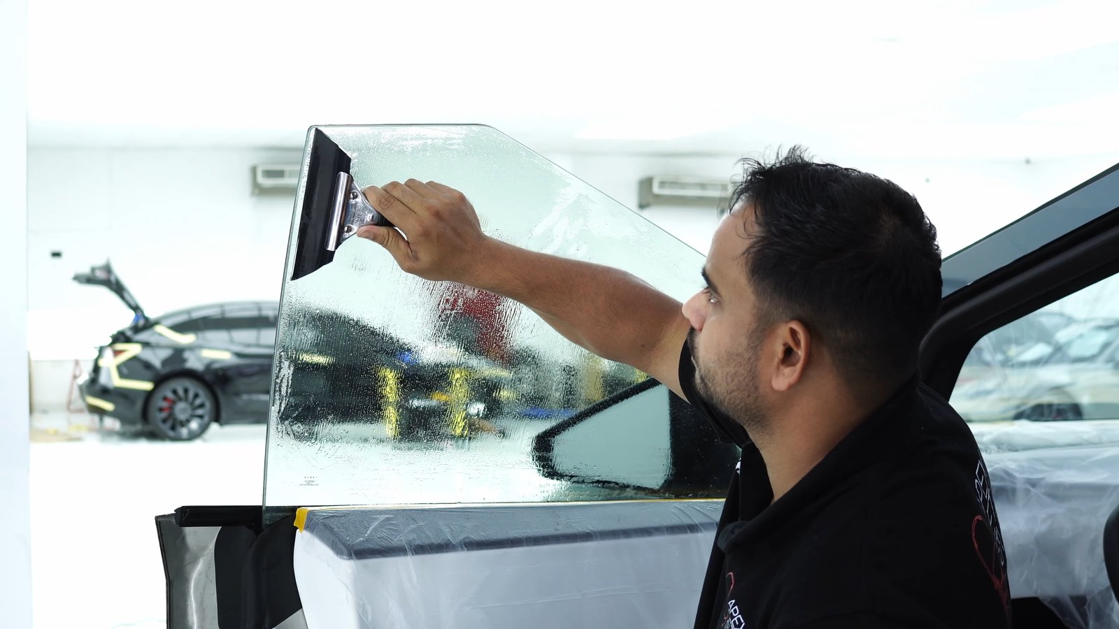 Technician cutting window film on the outside of a Tesla Cybertruck window