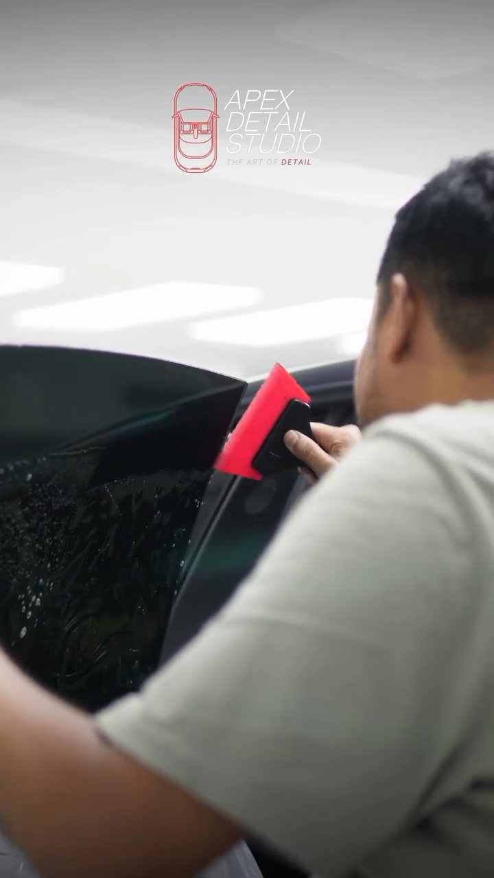 Close-up of the squeegee pushing water out of the Tesla Model 3 tint
