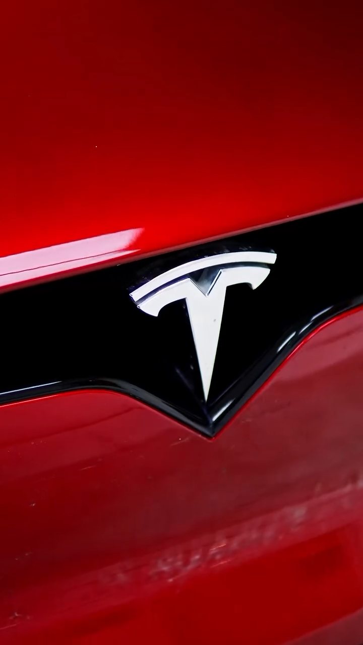 Tesla Model X badge on the original red paint before the colour change at Apex Detail Studio Dubai